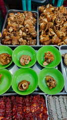 A display of pata or boiled pork knuckles, barbecue and isaw or chicken intestine skewers at a market stall. Authentic Filipino street food of the Philippines