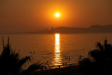 tropical beach sunset with city silhouette