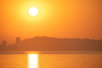 vibrant golden hour sunset casts an orange glow over a city skyline silhouetted against the...