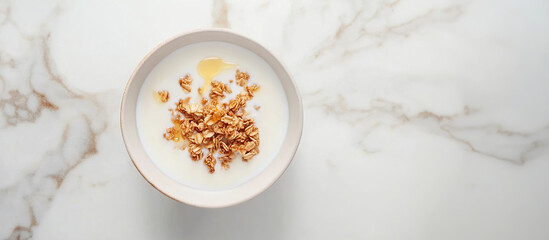 Bowl of yogurt with granola and honey on marble background. Top view