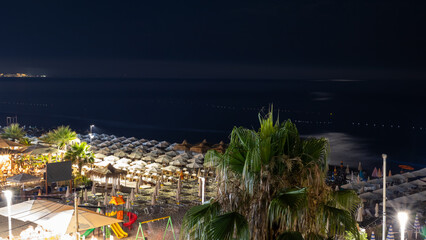 night view of a beach resort with illuminated umbrellas and dark sea