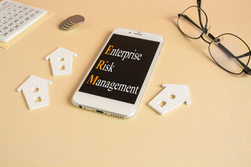 Concept words Enterprise Risk Management written on the mobile phone screen. Beautiful beige...