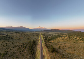 Amazing scenic aerial view of a road leading towards a snow covered volcano at sunrise, highway 97...