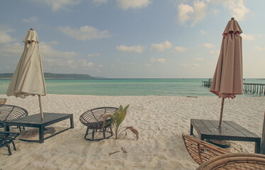 A serene beach setting with umbrellas, lounge chairs, and calm sea under a cloudy sky in Koh Rong...
