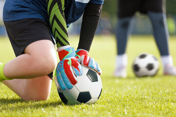 Young boy as a soccer goalie holding the ball in one hand ready to start a game. Football...