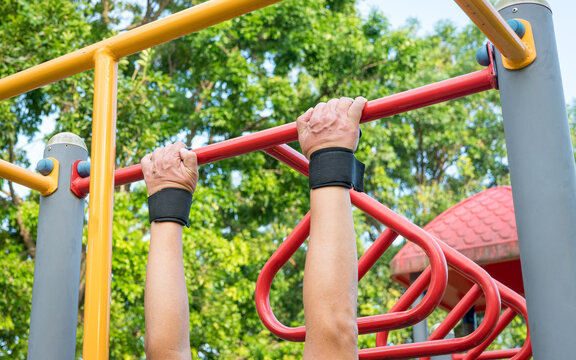 Man doing pull ups workout on the steel bar in the park.