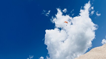 Man paragliding over coastal cliffs on a sunny day.
