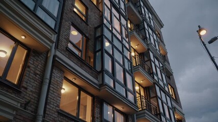 Modern apartment building illuminated at dusk in a bustling urban neighborhood