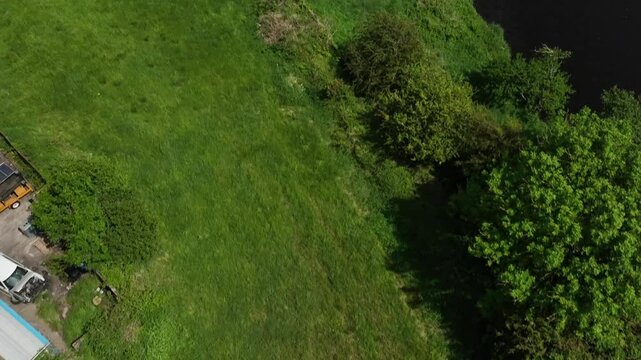 Clady Bridge, County Tyrone, Northern Ireland, June 2023. Drone top shot angled approach to arched bridge crossing over River Finn.