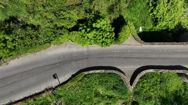Clady Bridge, County Tyrone, Northern Ireland, June 2023. Drone slow tracking right top shot bird's eye view above River Finn bridge with cloud and sky reflecting in water.