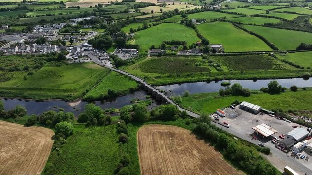 Clady Bridge, County Tyrone, Northern Ireland, June 2023. Drone panoramic high angle overview of arched bridge crossing River Finn with clouds reflecting in calm water.
