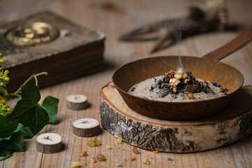 Incense ritual at wheel of the year festival Samhain with frankincense, myrrh and dried herbs in...