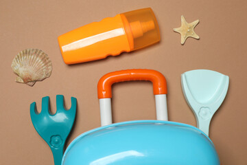 child's travel suitcase, toys, sugary cream on a beige background