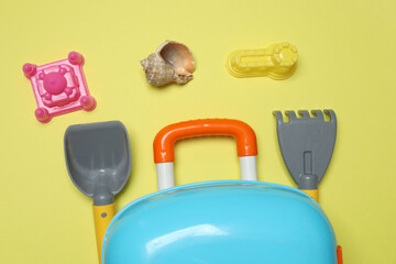 child's travel suitcase, toys, sweet cream on a yellow background