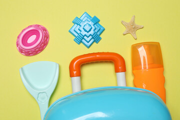child's travel suitcase, toys, sweet cream on a yellow background