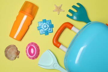 child's travel suitcase, toys, sweet cream on a yellow background