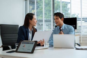 Business team analyzing documents, graphs, and data with a laptop, tablet, and smartphone. Collaboration, strategy, and success.