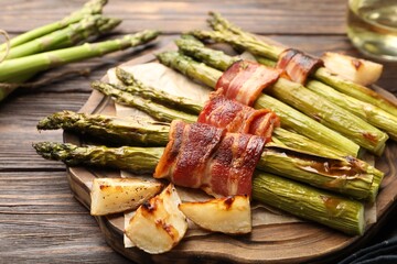Tasty cooked asparagus, bacon and potatoes on wooden table, closeup