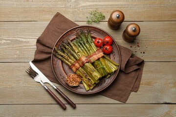 Tasty cooked asparagus served with bacon and spices on wooden table, flat lay