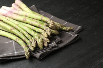 Fresh raw asparagus spears on black table, closeup. Space for text