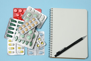 blisters of tablets, tablets, prescription notebook with space for text on a blue background