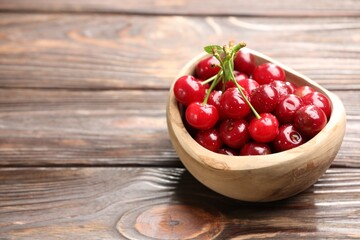 Fresh wet cherries in bowl on wooden table, closeup. Space for text