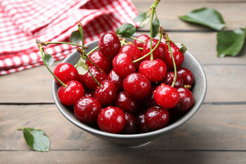 Fresh wet cherries in bowl on wooden table, closeup