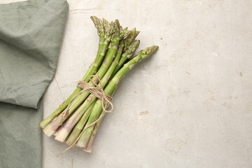 Fresh raw asparagus on light grey table, top view. Space for text