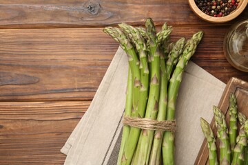 Fresh raw asparagus, spices and oil on wooden table, flat lay. Space for text