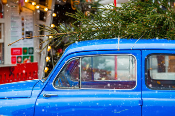 Concept of goods delivery. Christmas tree on the roof of a vintage blue Christmas car. Decorated...
