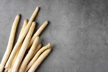 Many raw asparagus spears on grey table, flat lay. Space for text