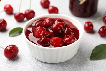 Tasty cherry jam and fresh fruits on light table, closeup