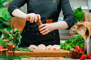 Chef effortlessly seasons fresh chicken with herbs and spices while surrounded by vibrant...