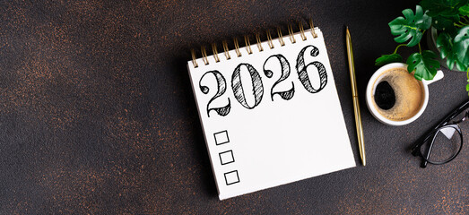New year resolutions 2026 on desk. 2026 goals list with notebook, coffee cup, plant on table....