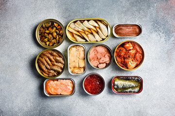 Top view of canned fish and seafood: tuna, salmon roe, sprats, cod liver and mackerel. On a light...
