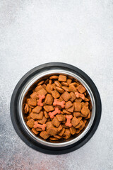 Metal Bowl with pet food. Organic grain food for dog or cat with meat flavour. Top view.