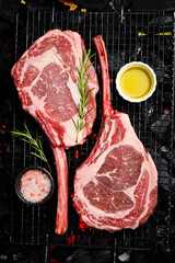 Two raw juicy Tomahawk steaks are cooked over hot coals. Barbecue. Top view.