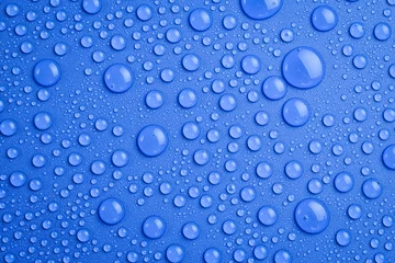 Fotobehang Water drops on an abstract blue background. Macro photo. Top view. © Yaruniv-Studio