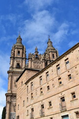 Fototapeta premium Baroque towers of the Clerecía Church against a vibrant blue sky in Salamanca Spain showcasing intricate stonework and historic architecture 