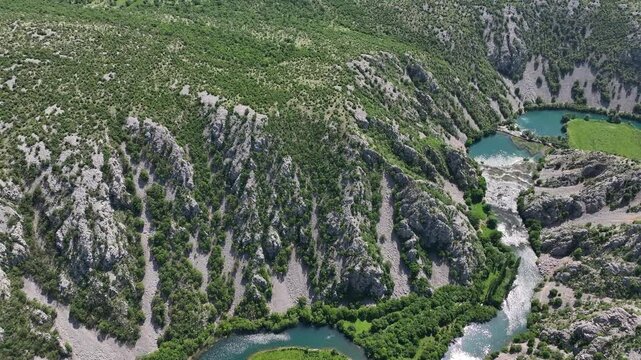 Aerial view where rivers Krnjeza and Krupa merge. Aerial shots of winding Zrmanja river cutting through deep canyon, lush spring colors and remote paths