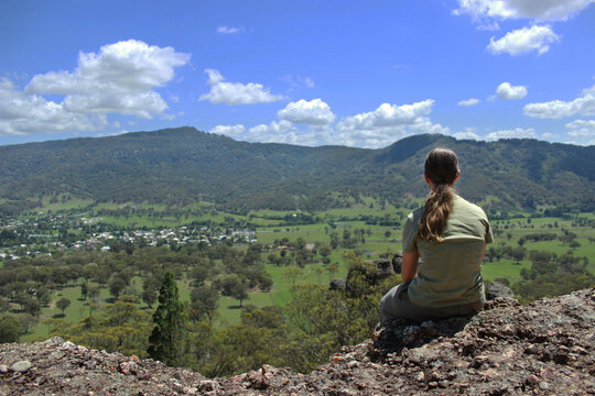 Girl sitting on a rocky ledge overlooking hills and valley