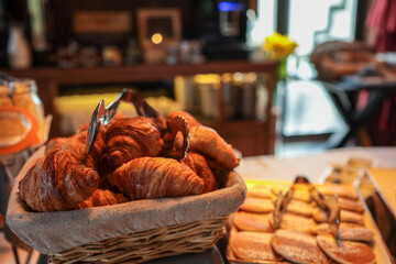 Hotel breakfast buffet with basket of croissants, assorted pastries, cakes, and desserts. Elegant...