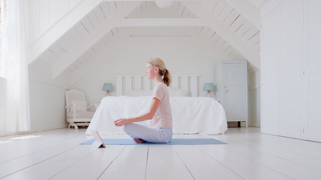 Woman With Digital Tablet Sitting In Bedroom Doing Yoga - Powered by Adobe