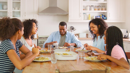 Family With Teenage Children Eating Meal In Kitchen At Home
