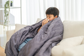 Young asian boy sneezing or blowing his nose and mouth with tissue, cold allergies or illness,...