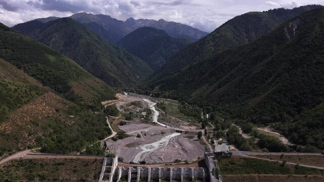 A protective dam against mudflows. Talgar gorge, Tian Shan Mountains. Different vegetation and a mountain river. The view from the drone.