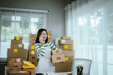 A young woman entrepreneur manages her online business from home, surrounded by parcel boxes, using a laptop, calculator, and notepad to handle shipping and inventory.