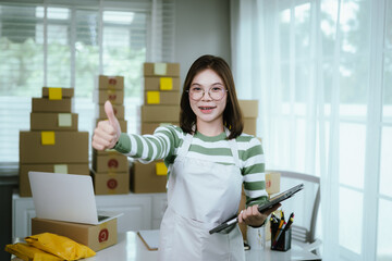 A young woman entrepreneur manages her online business from home, surrounded by parcel boxes, using a laptop, calculator, and notepad to handle shipping and inventory.