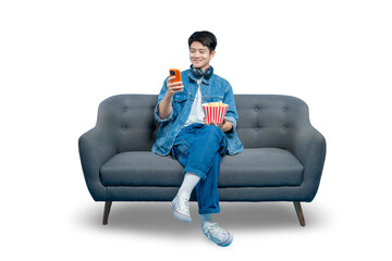 PNG,A young Asian man relaxes on a sofa with popcorn, smiling as he browses or texts on his smartphone.
