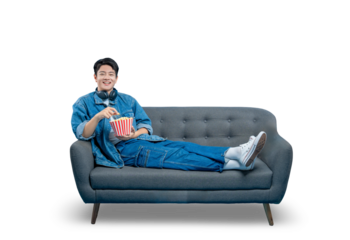 PNG,A relaxed young man lounging on a sofa reaches for popcorn while watching a movie or TV show.
